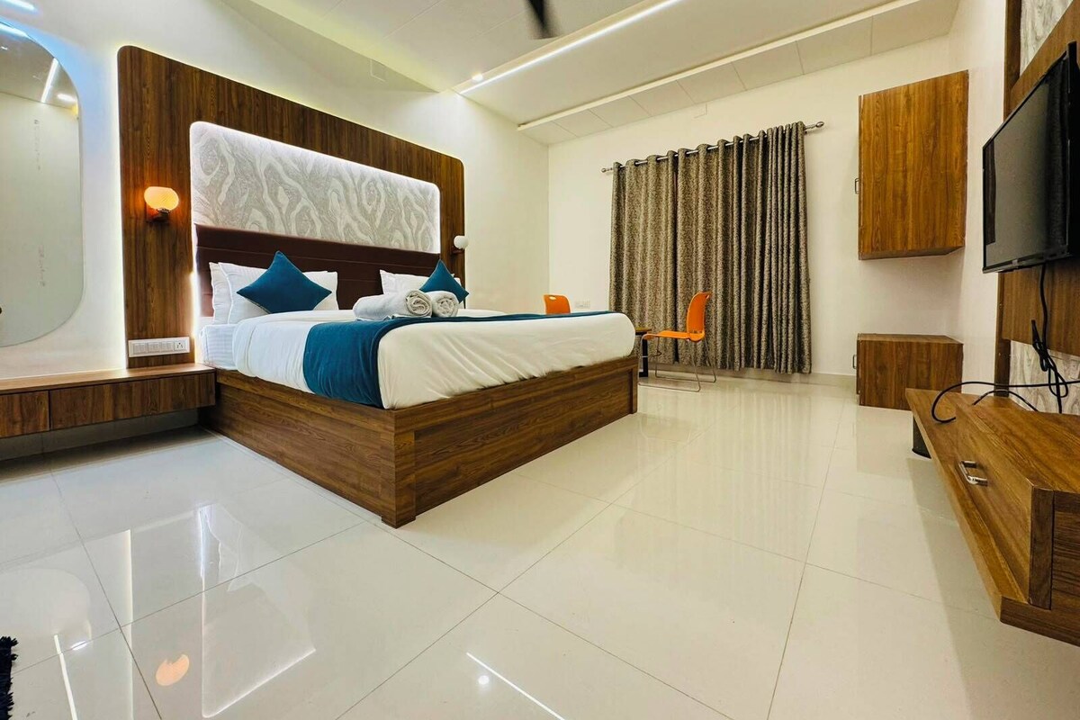 A modern hotel room with a large bed, a flat-screen TV, a ceiling fan, and a wooden wardrobe.
