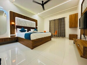 A modern hotel room with a large bed, a flat-screen TV, a ceiling fan, and a wooden wardrobe. - Sorathgadh Resort Sasan Gir (Sasan Gir)