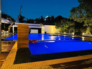A swimming pool with a blue surface, surrounded by a deck with yellow safety railings. - Sorathgadh Resort Sasan Gir (Sasan Gir)