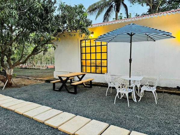 An outdoor seating area with a table and chairs, a bench, and a striped umbrella.