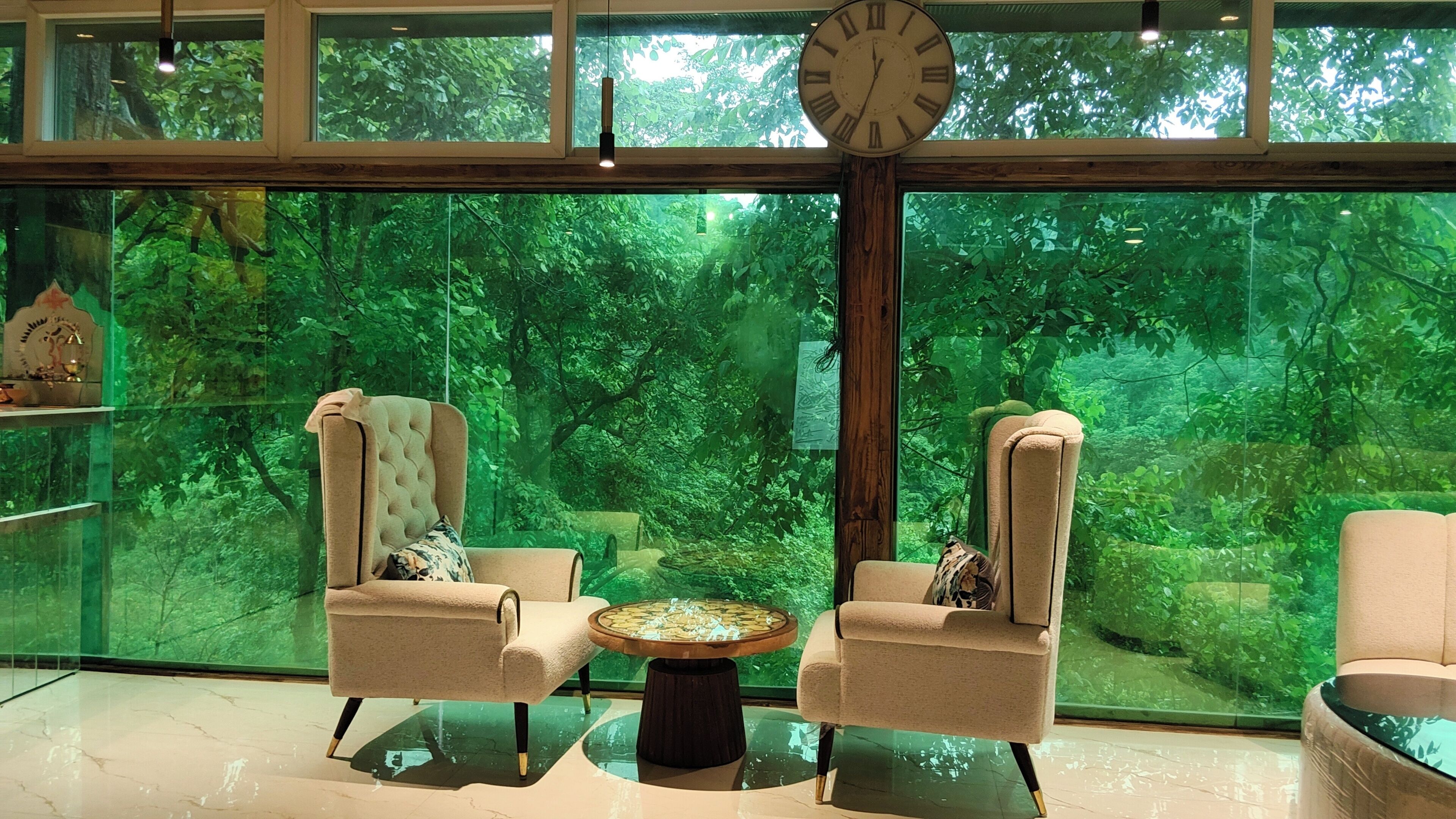 A room with two armchairs, a round table, and a large clock.