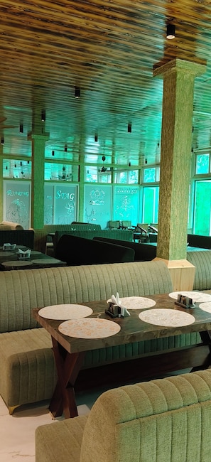 Un restaurante con asientos tapizados en verde, techo de madera y obras de arte enmarcadas en las paredes.