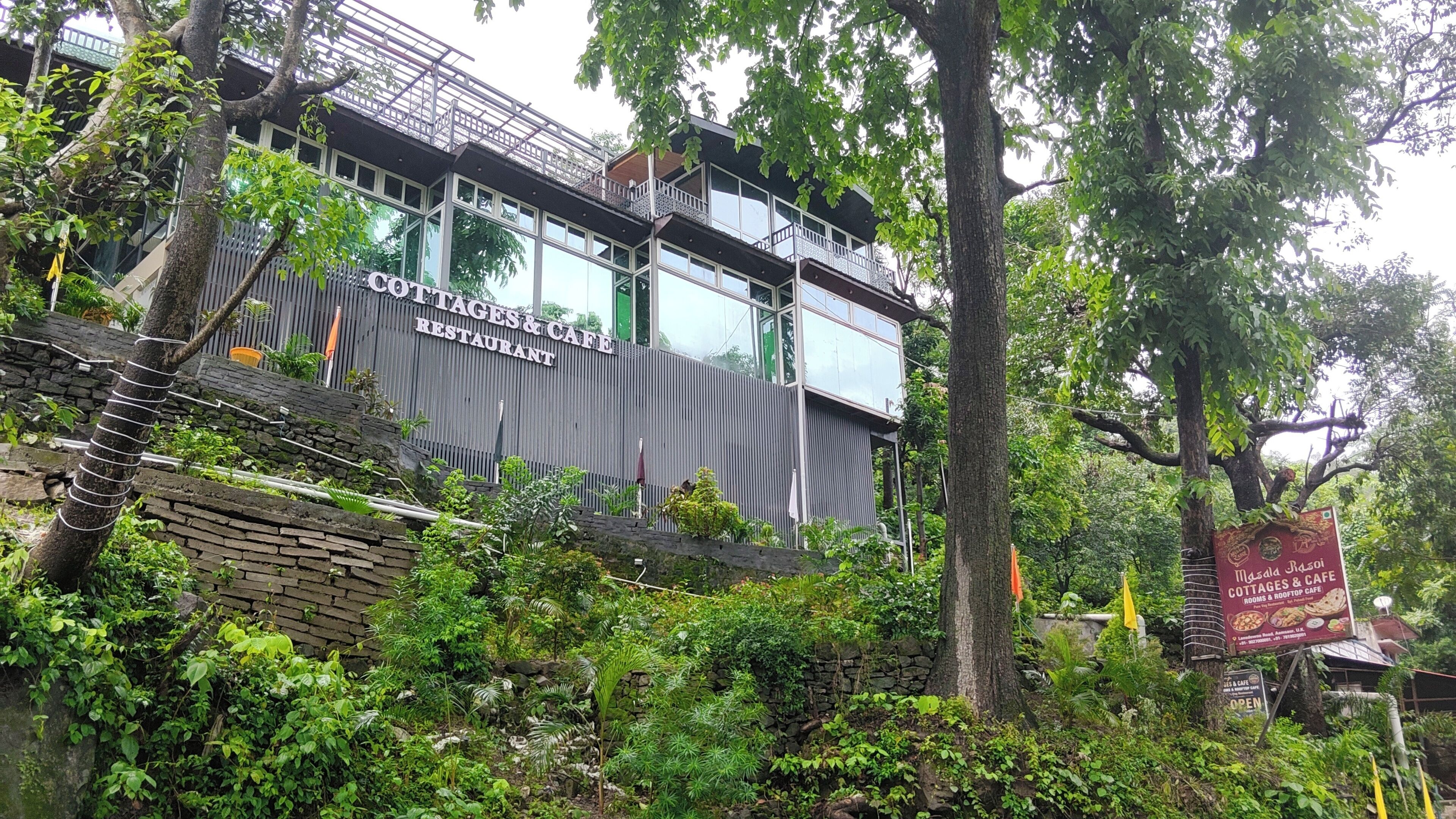 A multi-story building with a sign for 'COTTAGES & CAFE RESTAURANT' and a sign for 'MAASD RASOI COTTAGES & CAFE.'