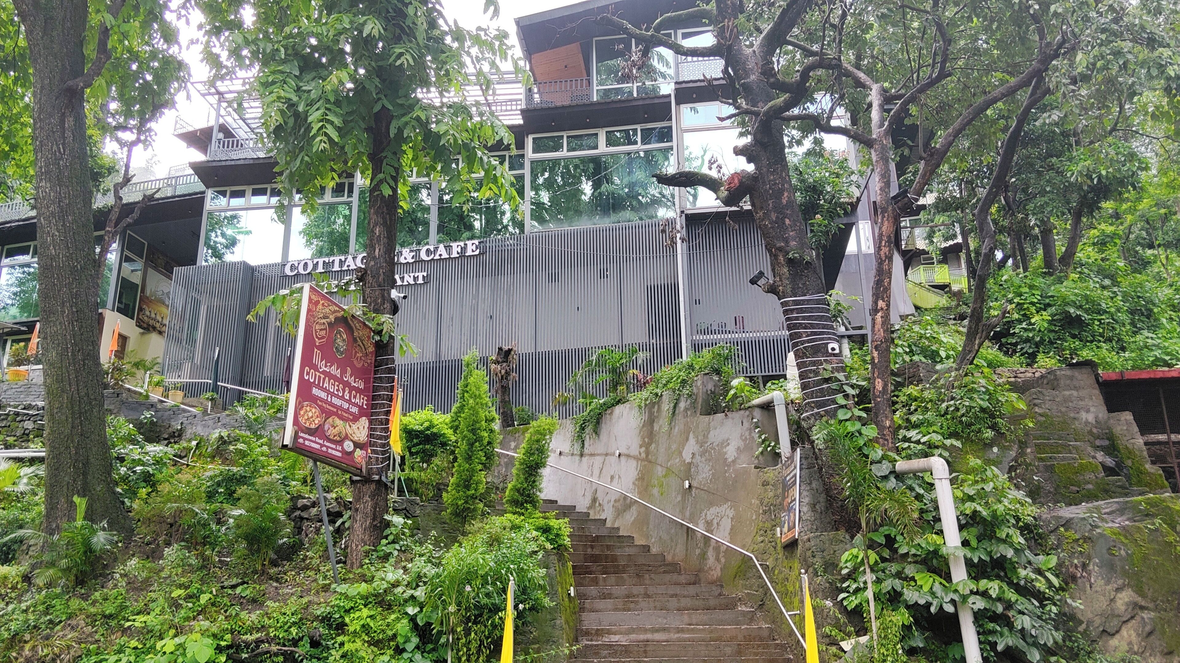 A staircase leading to a building with a sign for 'COTTAGES & CAFE' and a poster for 'Masa La Rosi.'