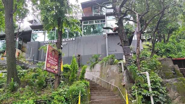 A staircase leading to a building with a sign for 'COTTAGES & CAFE' and a poster for 'Masa La Rosi.' - Cottages & Cafe (Kotdwar)