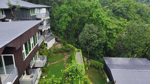 Un edificio de varios pisos con balcones, rodeado de vegetación exuberante y un cielo despejado.