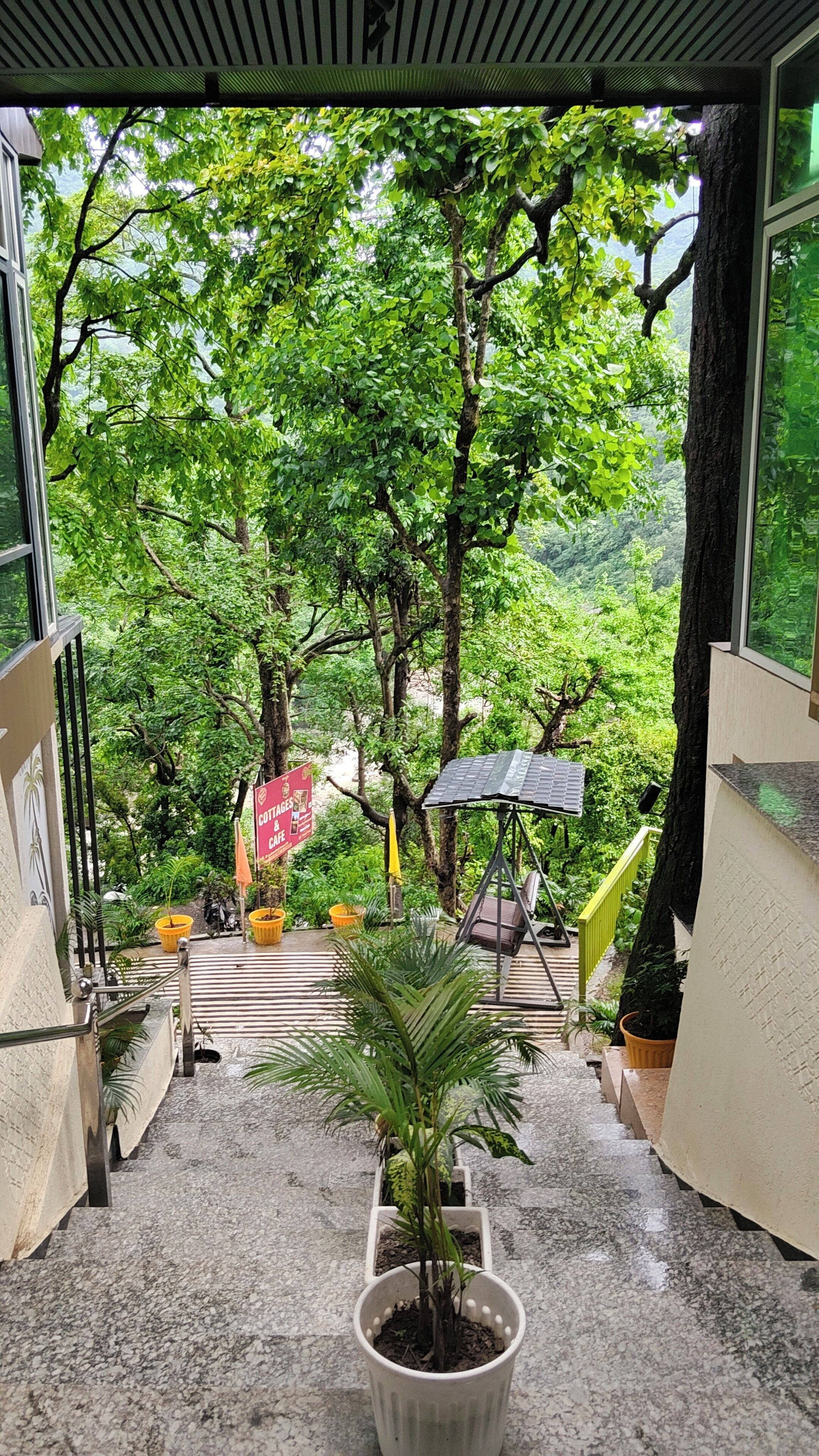 Un escalier menant à une terrasse d’où l’on peut admirer une végétation luxuriante, ainsi qu’une enseigne indiquant la présence de chalets et d’un café.
