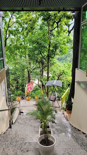 Una escalera conduce a una terraza con vistas a exuberante vegetación y un letrero de Cottages & Cafe.