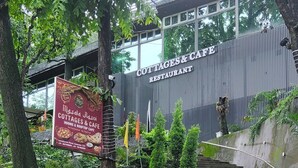 En trappe fører op til en bygning med skilte for 'COTTAGES & CAFE RESTAURANT' og 'Mdsala Rdsoi COTTAGES & CAFE'.
