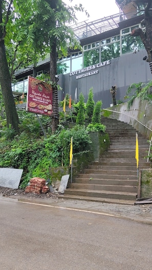 Una escalera conduce a un edificio con un letrero que dice 'COTTAGES & CAFE RESTAURANT' y otro letrero que dice 'Mdsala Rdsoi COTTAGES & CAFE'.