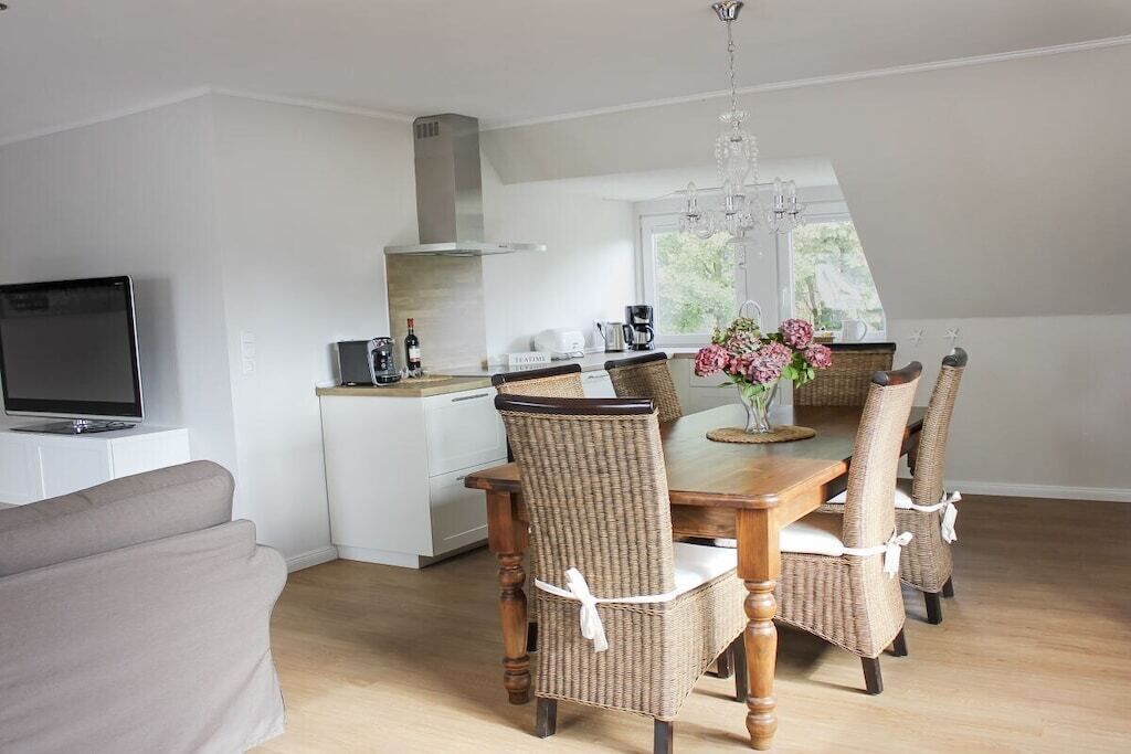 A modern kitchen with a dining area, a television, and a chandelier.