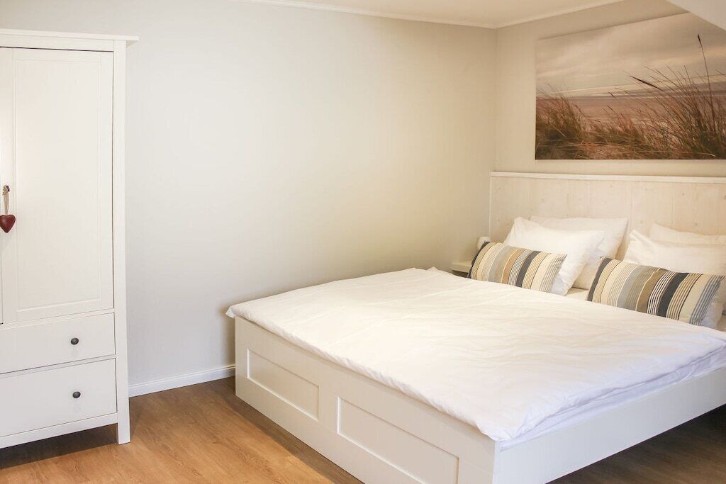 A bedroom with a bed, a wardrobe, and a painting on the wall.
