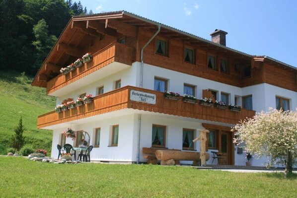 A two-story building with a balcony, a sign indicating it is a guesthouse, and a log placed outside. - "Kehstein" in the "Bartmann" house (Ramsau)