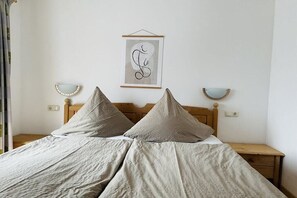 A bed with a wooden headboard, two bedside tables, and a wall-mounted picture. - "Kehstein" in the "Bartmann" house (Ramsau)