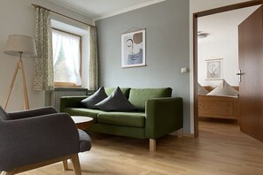 A room with a green sofa, a wooden floor, a lamp, and a bed with a wooden headboard. - "Kehstein" in the "Bartmann" house (Ramsau)