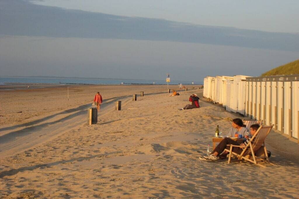 Una playa con una valla de madera, una torre de salvavidas y gente relajándose.