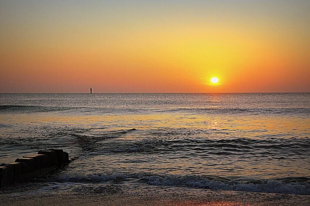 Ein Sonnenuntergang über einem ruhigen Meer mit einer felsigen Küste.