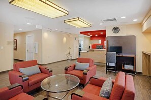 A hotel lobby with red sofas, a glass coffee table, a reception desk, and a clock on the wall. - Your Home Base Near Philly + Free Parking. Kitchen (Mount Laurel)