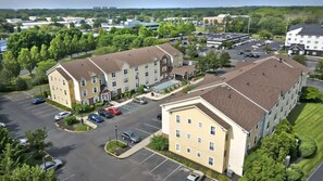 A multi-story hotel with a parking lot, surrounded by greenery.