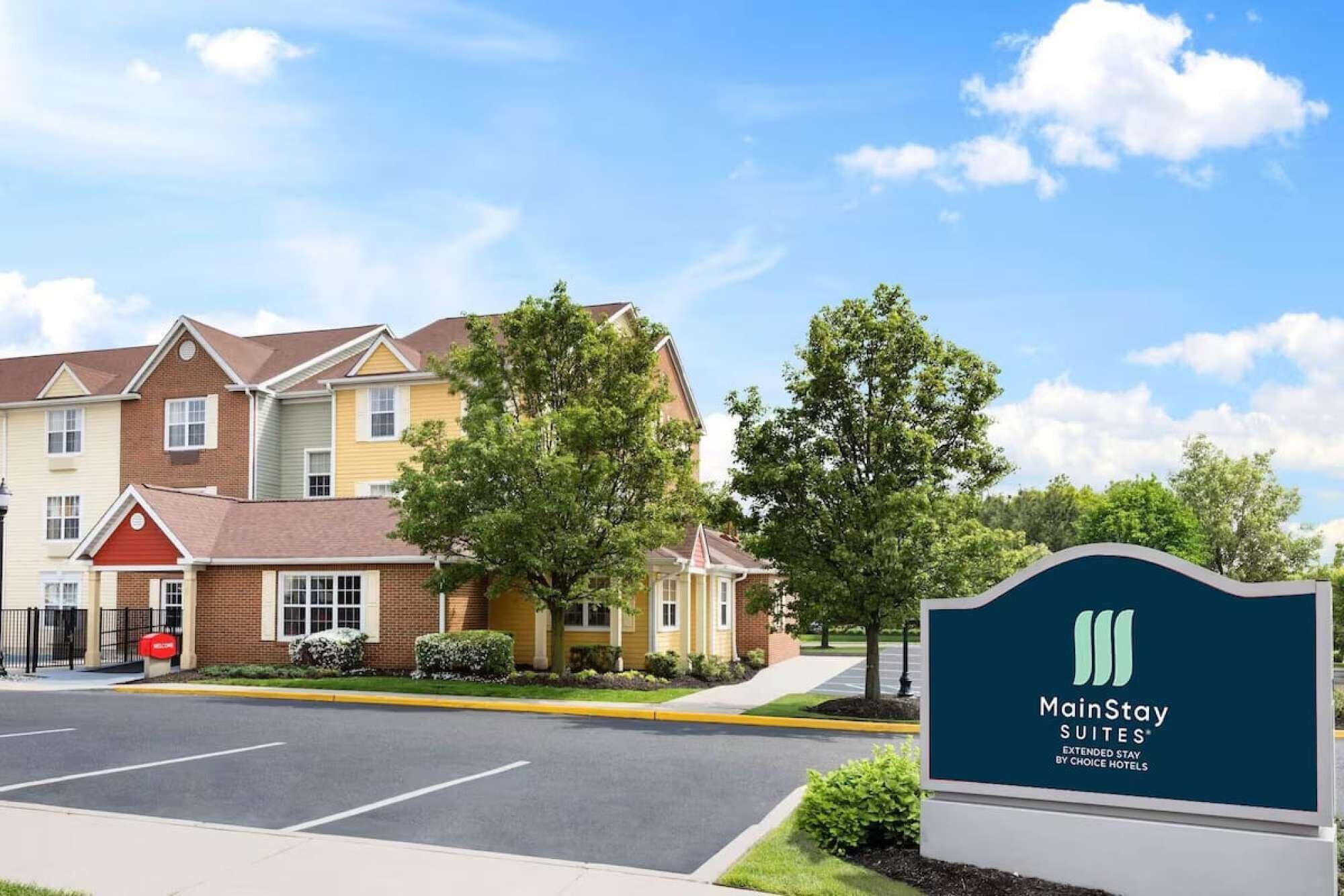 A MainStay Suites hotel with a parking lot and a signboard.