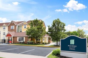 A MainStay Suites hotel with a parking lot and a signboard.