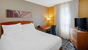 Hotellihuone, jossa on sänky, työpöytä, tuoli, televisio ja lamppu.