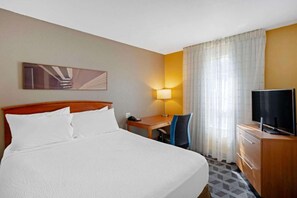A hotel room with a bed, a desk, a chair, a television, and a lamp. - Near Cherry Hill + Full Kitchens & Free Parking (Mount Laurel)