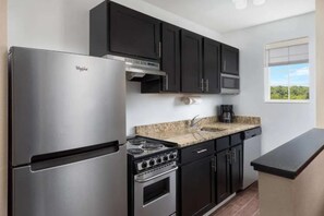 A modern kitchen with a stainless steel refrigerator, a gas stove, and dark cabinetry.