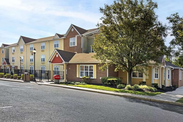 A row of townhouses with a central entrance, a well-maintained lawn, and a clear sky. - Near Cherry Hill + Full Kitchens & Free Parking (Mount Laurel)