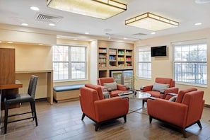 A modern living room with a seating area, a bookshelf, and a television.