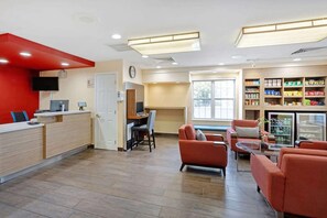 A modern interior with a reception desk, seating area, and a refrigerator stocked with snacks.