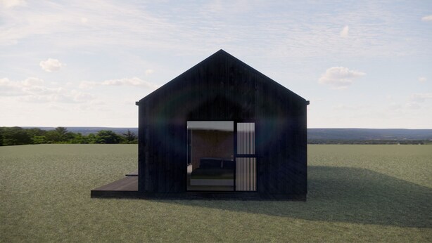 A small, dark-colored, single-story building with a triangular roof, situated on a grassy field with a distant view. - Þjórsárdalur Lodges & Cabins (Skeiða- og Gnúpverjahreppur)