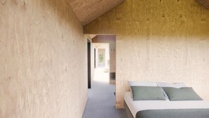 A room with a wooden ceiling, a bed with green pillows, and a visible hallway leading to another room. - Þjórsárdalur Lodges & Cabins (Skeiða- og Gnúpverjahreppur)