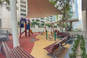 Ein Spielplatz mit Rutsche, Schaukeln und Bänken.