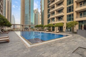 A rooftop swimming pool with lounge chairs and a view of surrounding high-rise buildings. - Prime Downtown Studio Near Burj Khalifa (Dubai)