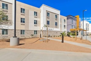 Een modern hotelgebouw met meerdere verdiepingen, een bord met 'EVERHOMESUITES' en een aangelegde omgeving met palmstruiken.