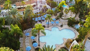 A resort with a central pool, lounge areas, and palm trees. - Near The Shops at Dos Lagos | Full Kitchen & Gym (Corona)