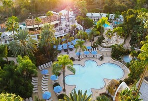 Een resort met een centraal gelegen zwembad, loungegedeeltes en palmbomen.