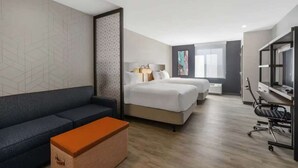 Habitación de hotel con sofá, dos camas, televisor y zona de ejercicios.