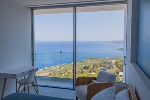 A modern room with a large sliding glass door leading to a balcony with a sea view. - The Luminous Villa: private estate, 4 sea-view suites, heated pool, sleeps 8 (Volimes)