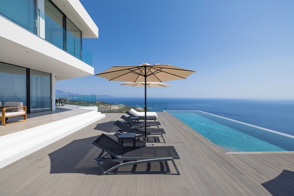 A modern outdoor deck with lounge chairs and a pool overlooking the sea. - The Luminous Villa: private estate, 4 sea-view suites, heated pool, sleeps 8 (luminous villa)