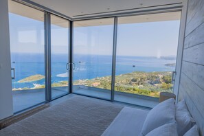 A bedroom with a large glass door leading to a balcony with a sea view. - The Luminous Villa: private estate, 4 sea-view suites, heated pool, sleeps 8 (luminous villa)