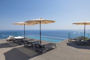 A poolside area with lounge chairs and umbrellas, overlooking a clear blue ocean. - The Luminous Villa: private estate, 4 sea-view suites, heated pool, sleeps 8 (luminous villa)