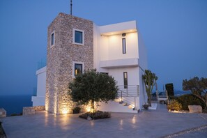A modern building with a stone facade, a staircase, and a view of the sea. - The Luminous Villa: private estate, 4 sea-view suites, heated pool, sleeps 8 (luminous villa)