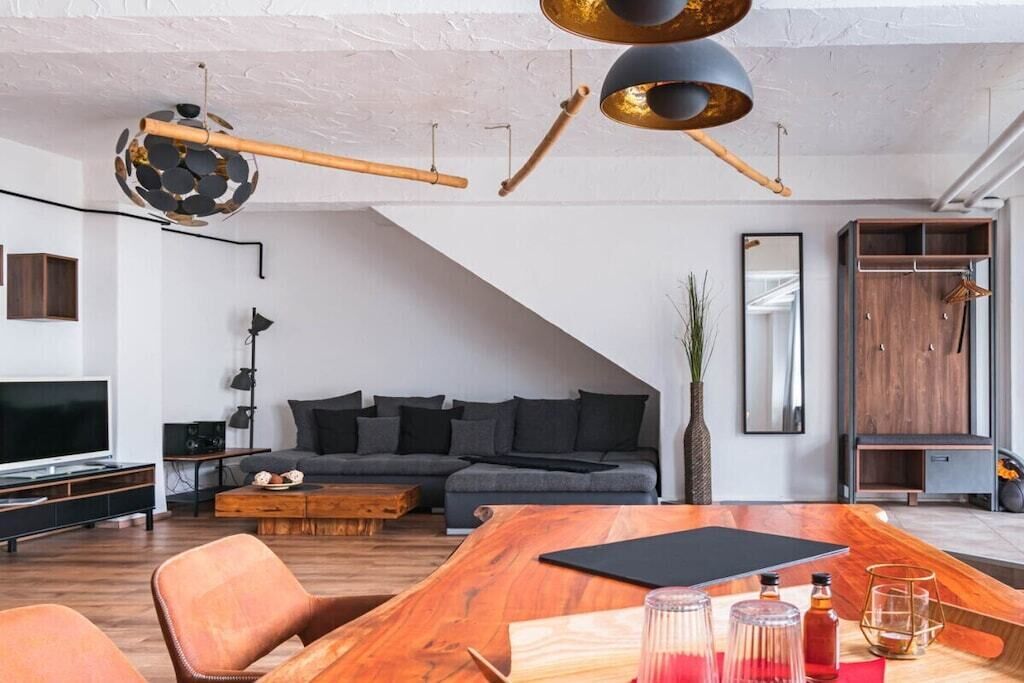 Una sala moderna con una mesa de comedor de madera, un sofá y una televisión.