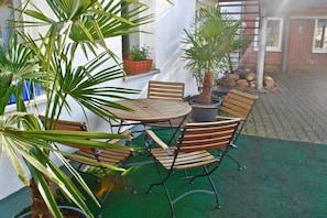 An outdoor seating area with a round table and chairs, surrounded by potted plants. - Holiday apartment with 1 bedroom (Warnemünde)
