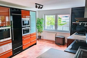 A modern kitchen with built-in appliances, a window with a view, and a potted plant. - Baltico Design Apartment (Rostock)