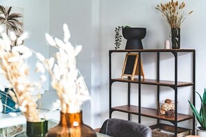 A modern interior with a black metal shelving unit, a small wooden easel, and decorative plants.