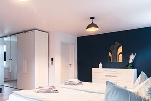 A modern bedroom with a bed, bedside tables, a wardrobe, and a mirror on the wall.