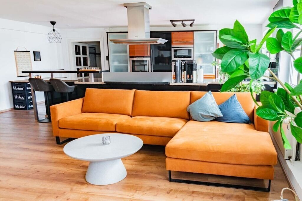 A modern living room with a sectional sofa, a coffee table, and a kitchen in the background.